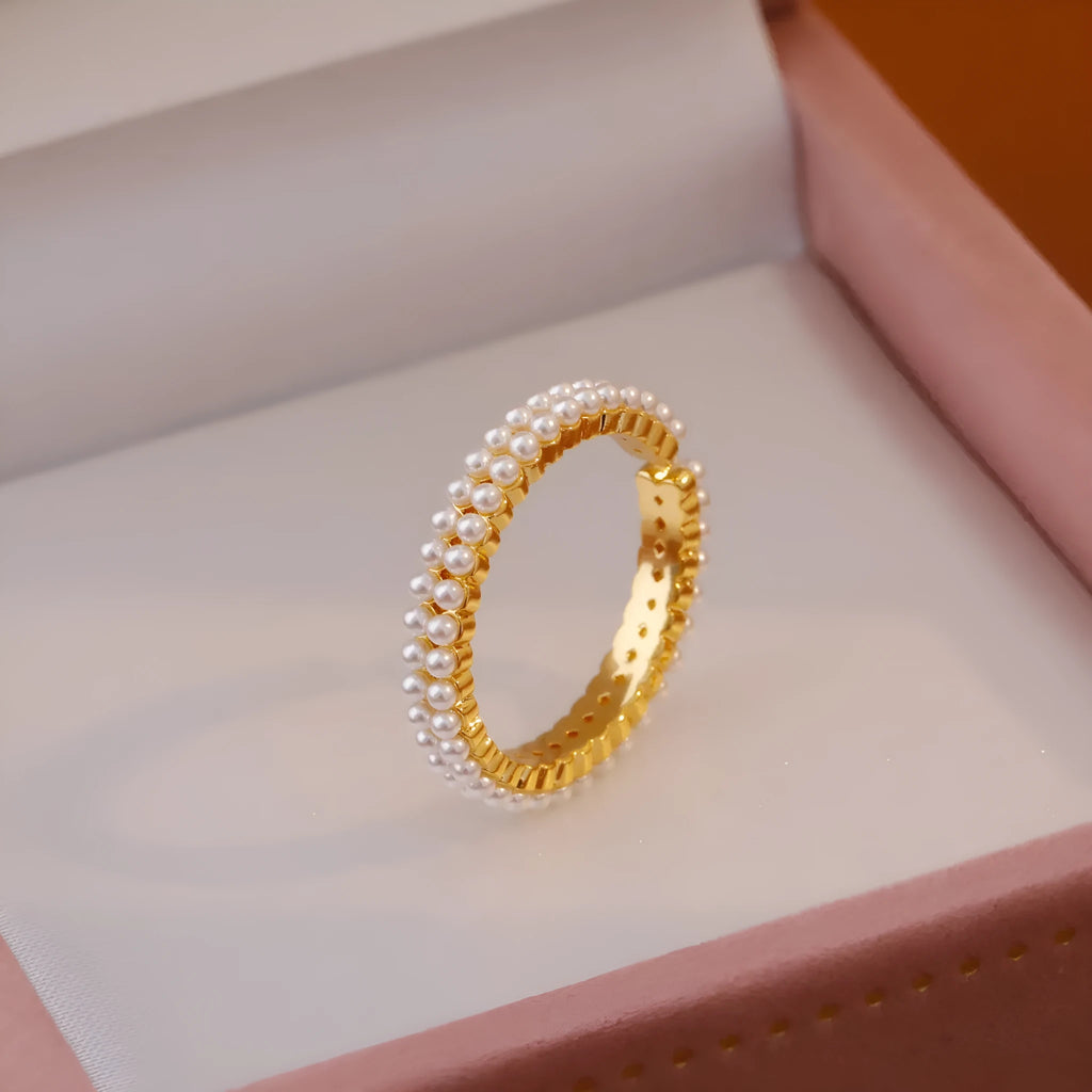 Gold geometric open ring with pearl detail on a model's finger.
