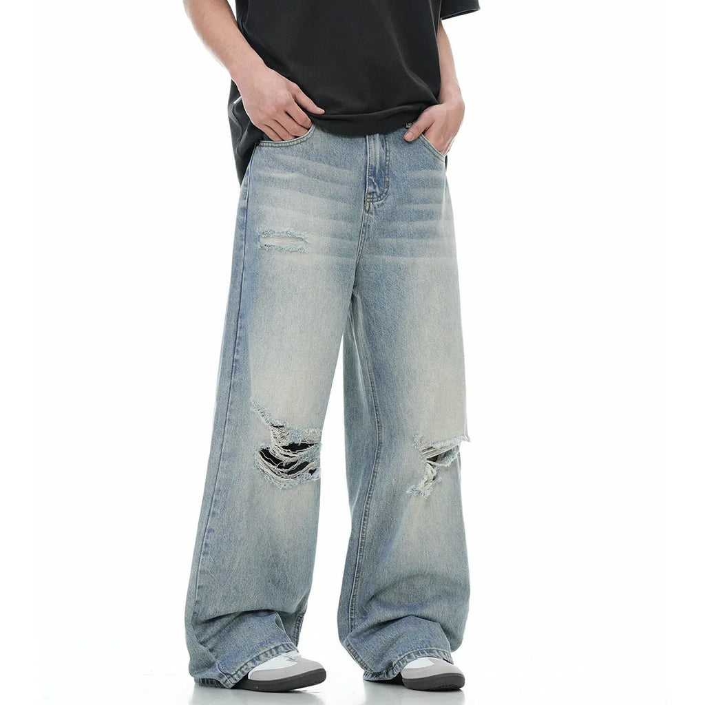 Man wearing blue retro-style straight-leg jeans with a ripped, distressed finish on the legs.