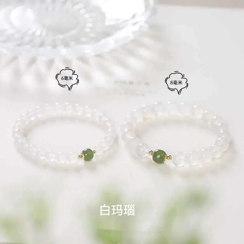 Handmade white agate and Hetian jade crystal bracelet with cinnabar accents on a wrist.