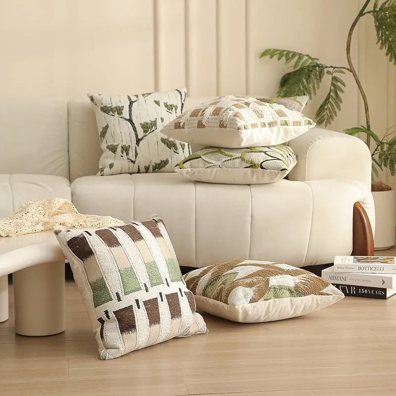 Square jacquard pillow cover with botanical pattern on a sofa, showing one of eight available colour options.