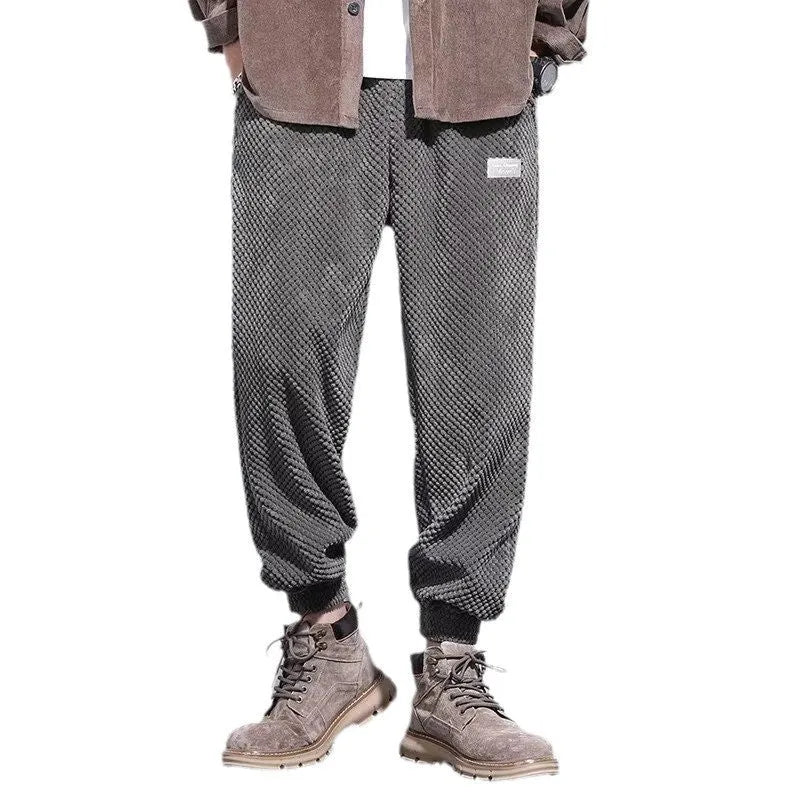 Man wearing grey straight-leg casual sweatpants with an ankle-tied design detail.