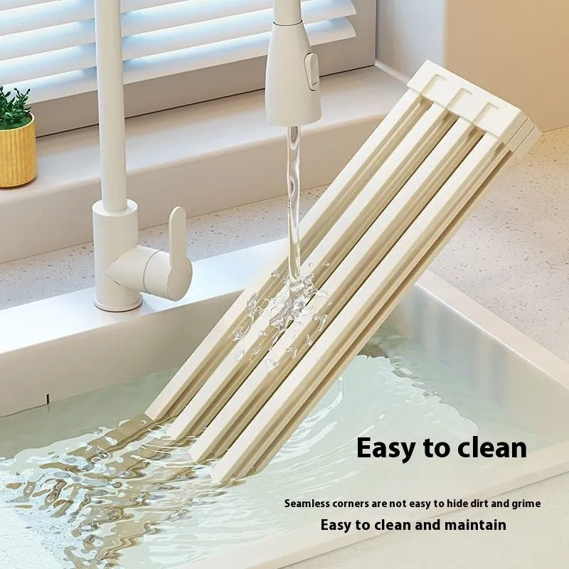 Foldable milky white stainless steel kitchen draining rack beside a sink