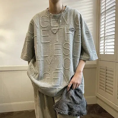 Men's loose fit grey t-shirt with a raised black three-dimensional retro letter print on the front.