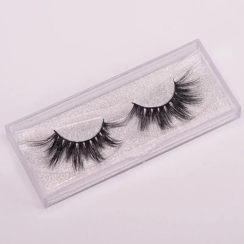 A pair of 5D mink false eyelashes with a hair cap and double-headed brush on a white background.