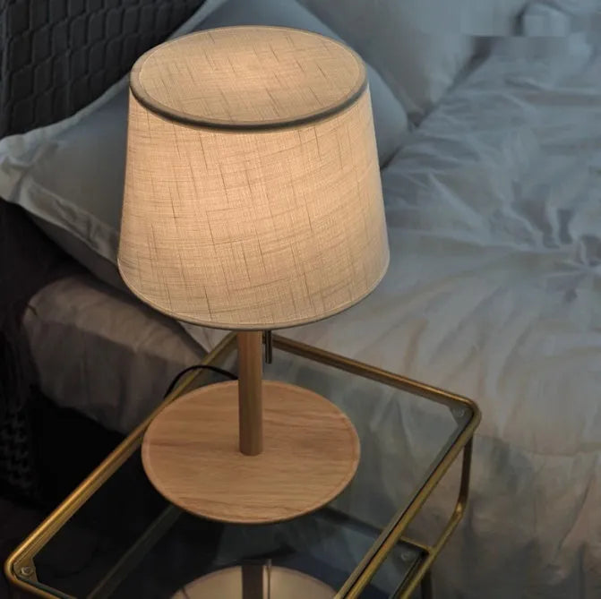Walnut colour solid wood table lamp with a white cloth shade and a black cable switch