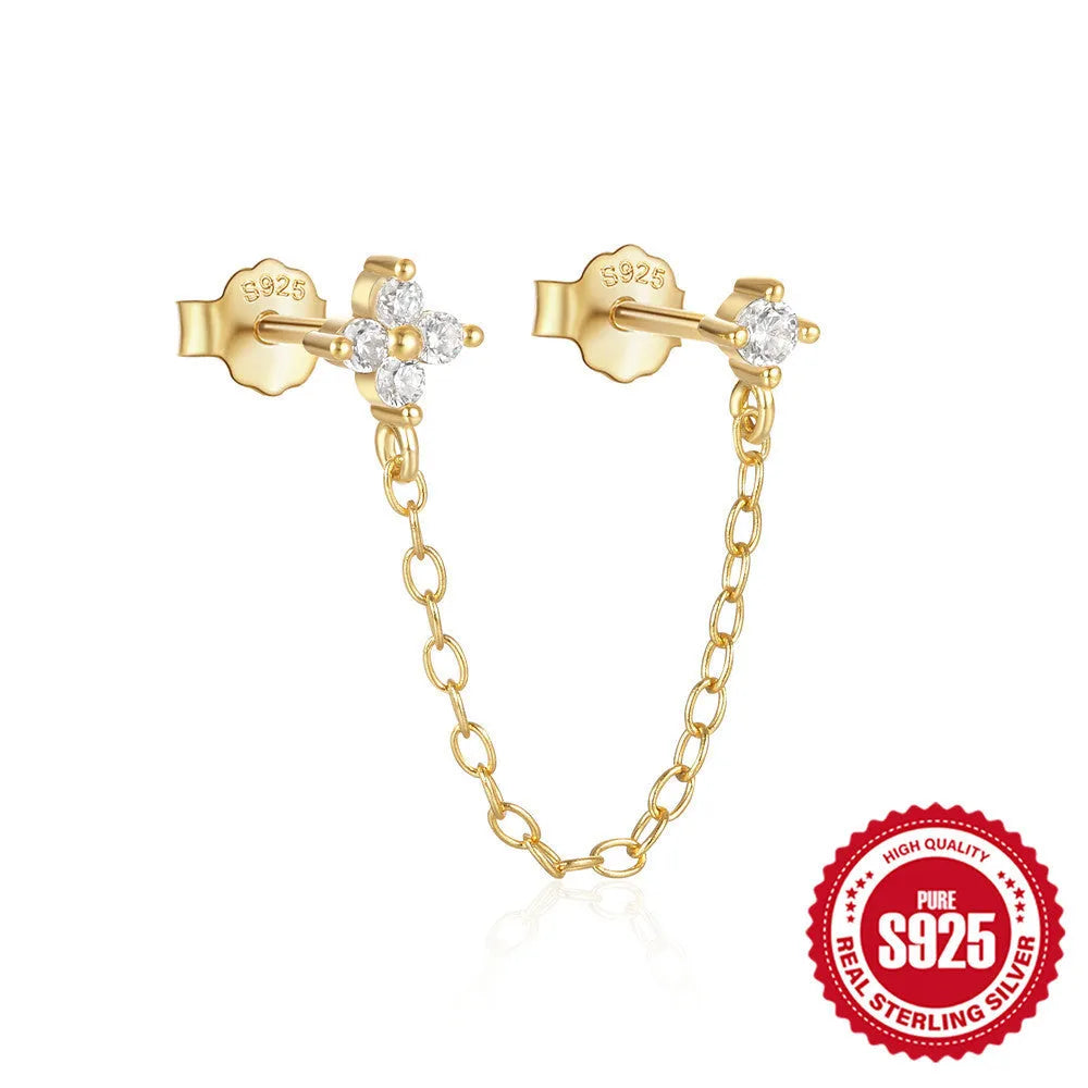 Close-up of a sterling silver stud earring with a geometric flower shape and dangling gold-tone tassel and chain details.