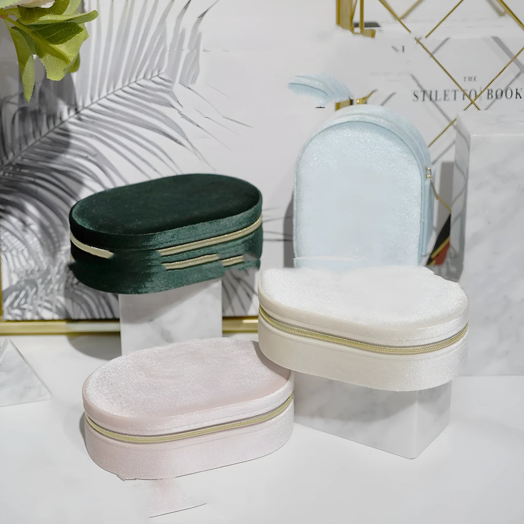 Oval shaped velvet jewellery storage box in lake blue colour with internal compartments and a red hook.