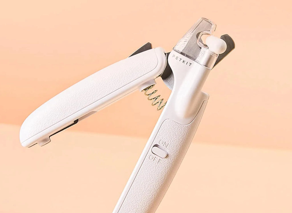 White pet nail clippers with LED light, transparent anti-splash guard, and integrated nail file on a grey background.