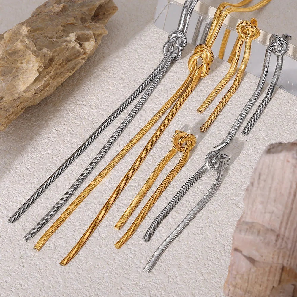 Gold colour titanium steel necklace with knotted tassel pendant and matching earrings on a white background.