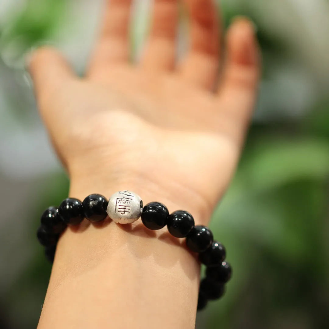 Handmade women's black agate bracelet with 10mm beads and a sterling silver clasp on a wrist.
