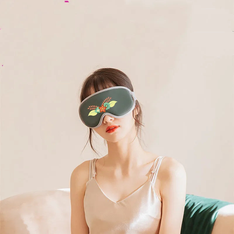 Portable green eye steam massage mask with USB cable on a grey background