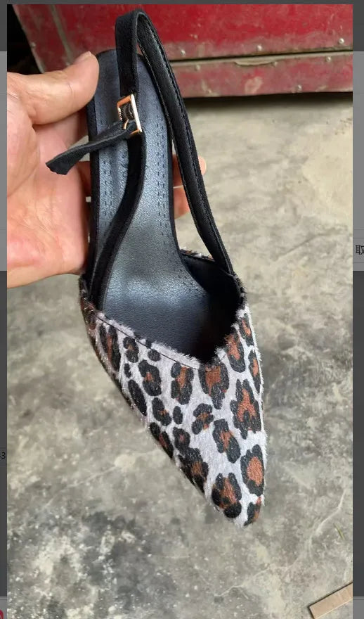 Leopard print women's suede sandals with a scattered pointed toe and high heel on a neutral background.