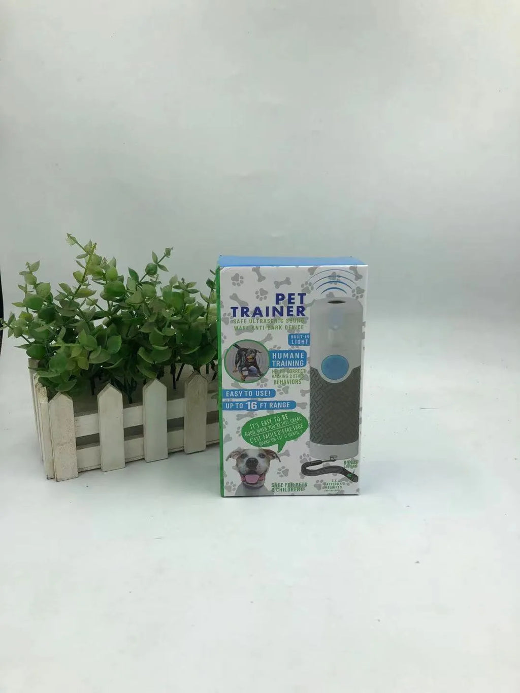 White handheld ultrasonic dog bark control trainer on a plain background.