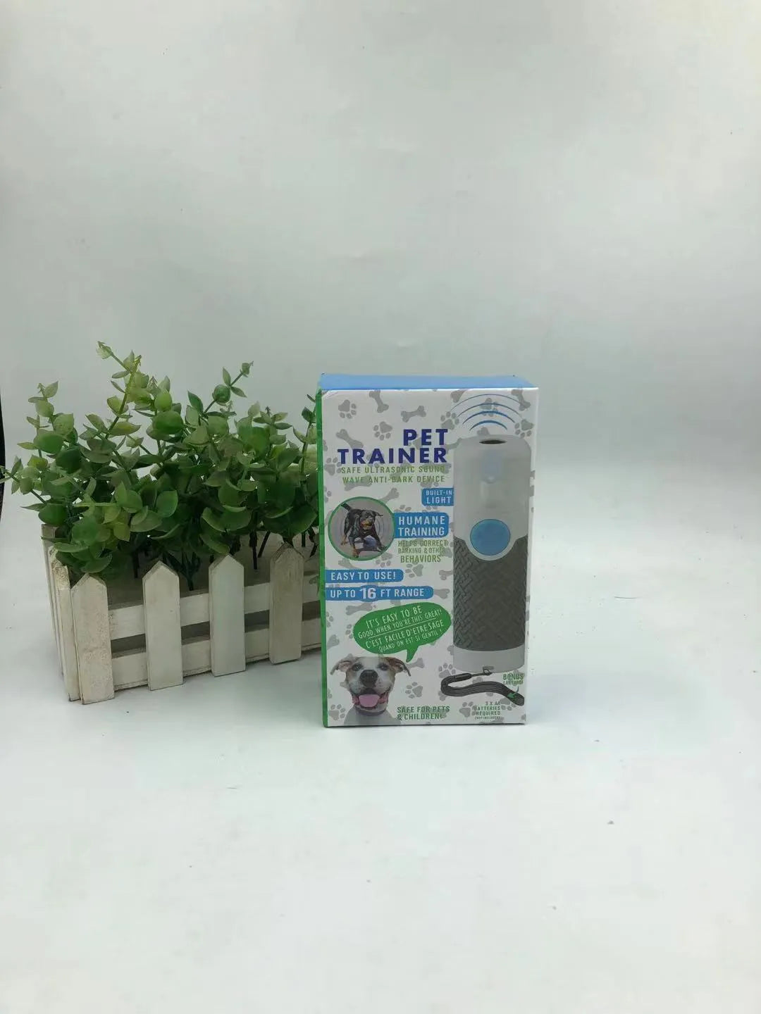 White handheld ultrasonic dog bark control trainer on a plain background.