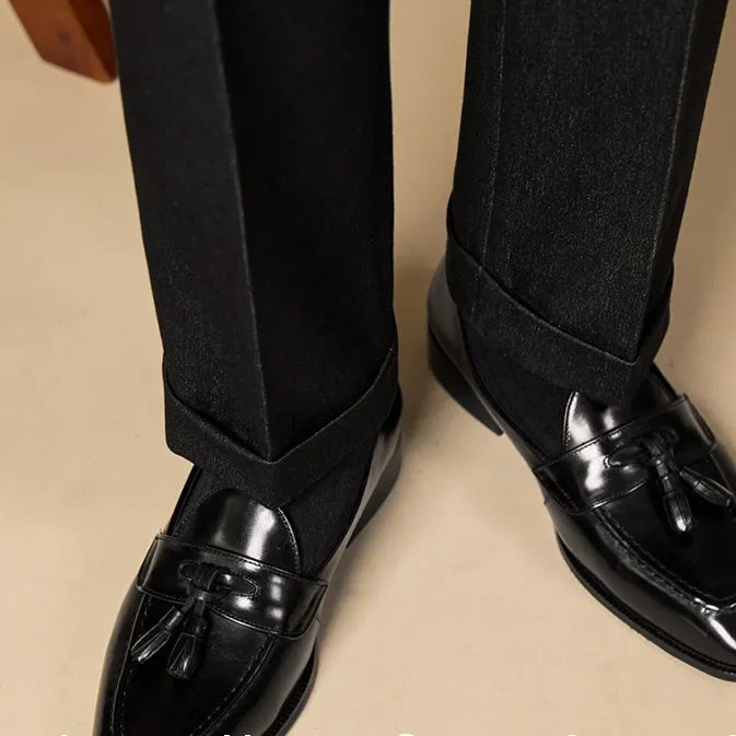 Men's black and brown genuine leather tassel loafers on a white background.