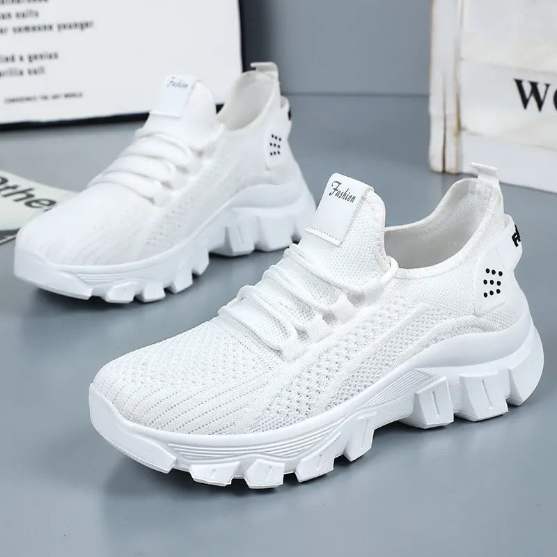 Women's white Flyknit running sneakers with lace-up front and thick PVC sole on a neutral background.