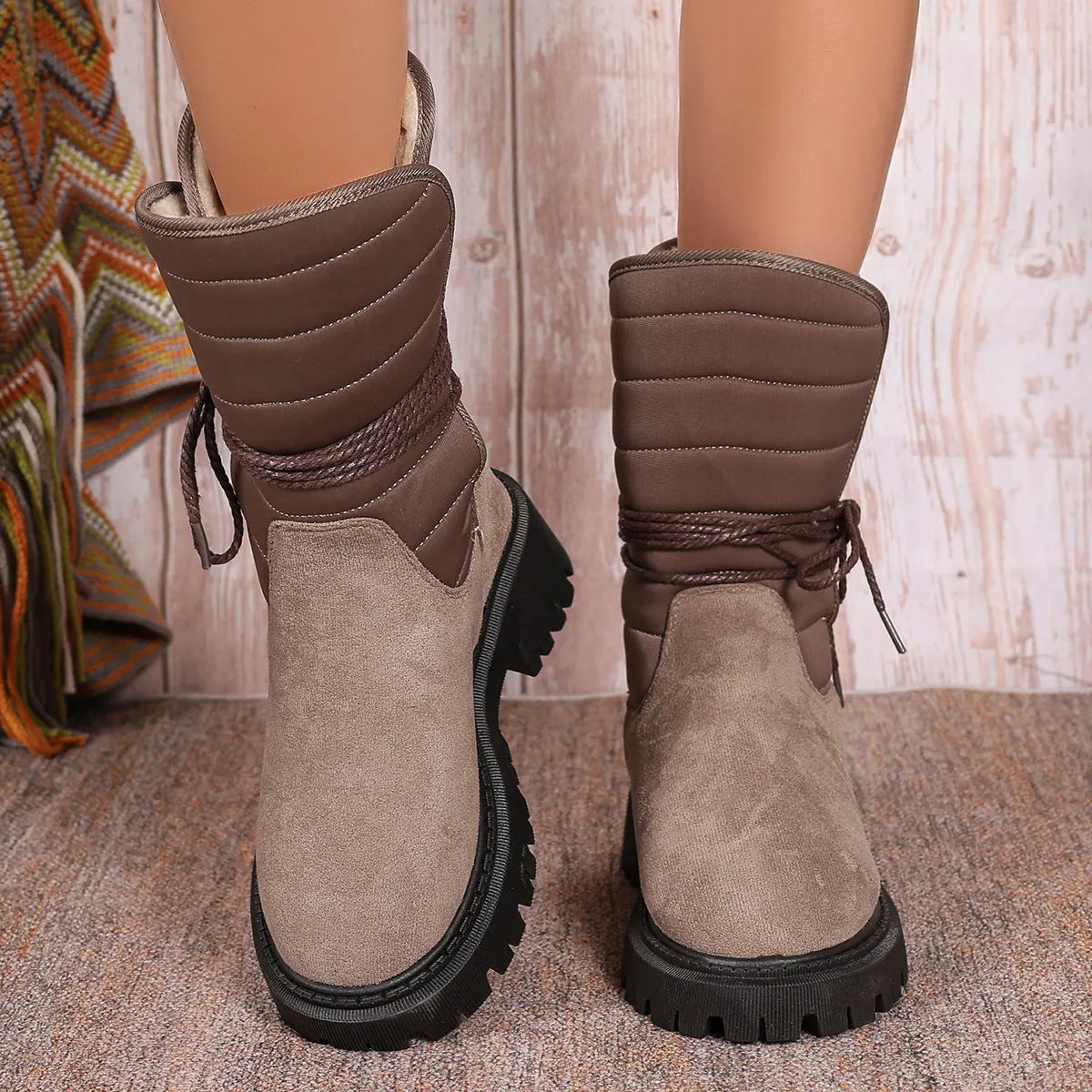 Women's black suede chunky heel snow boots with lace-up front and fleece lining shown on a winter background.