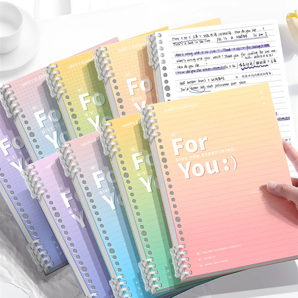 Removable coil-bound gradient colour notebook in A4 and B5 sizes on a desk.