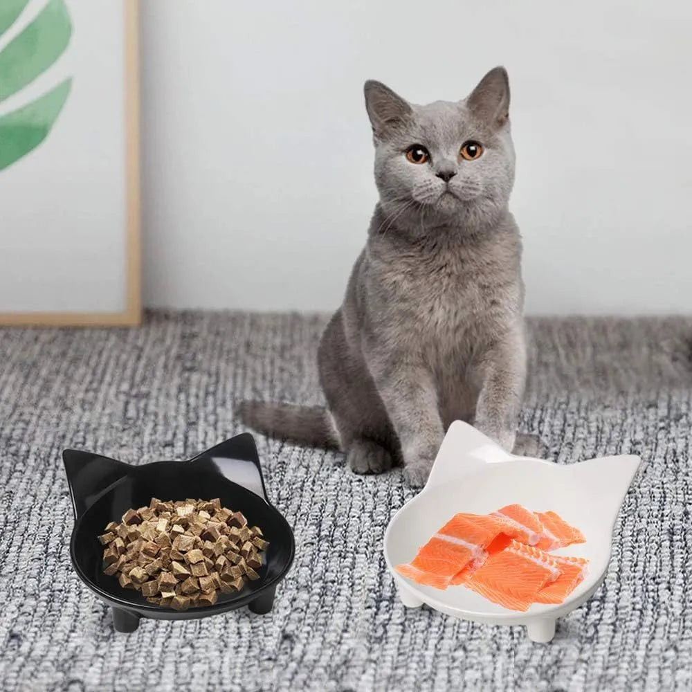 Four shallow black melamine pet bowls with non-slip rubber bases on a table.