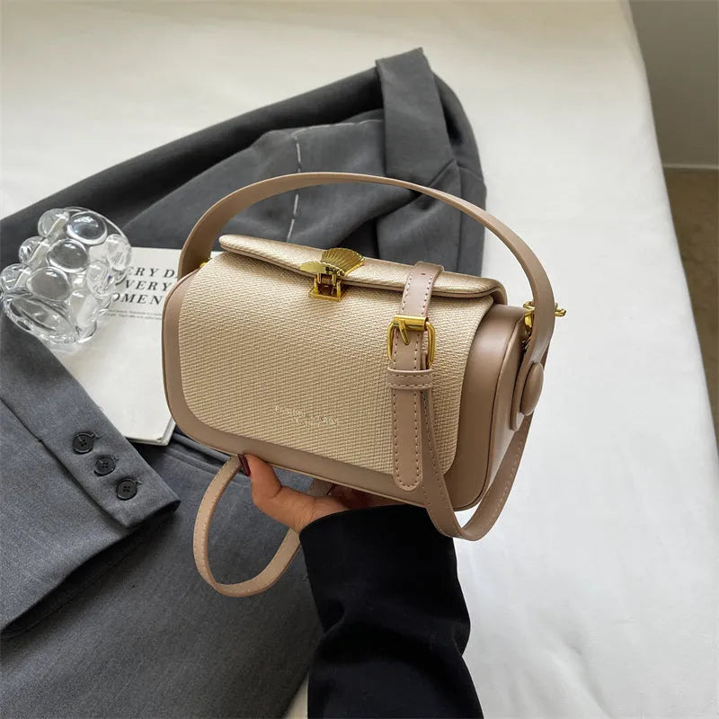 Structured women's PU leather messenger bag in a horizontal square shape with contrast stitching on a table.