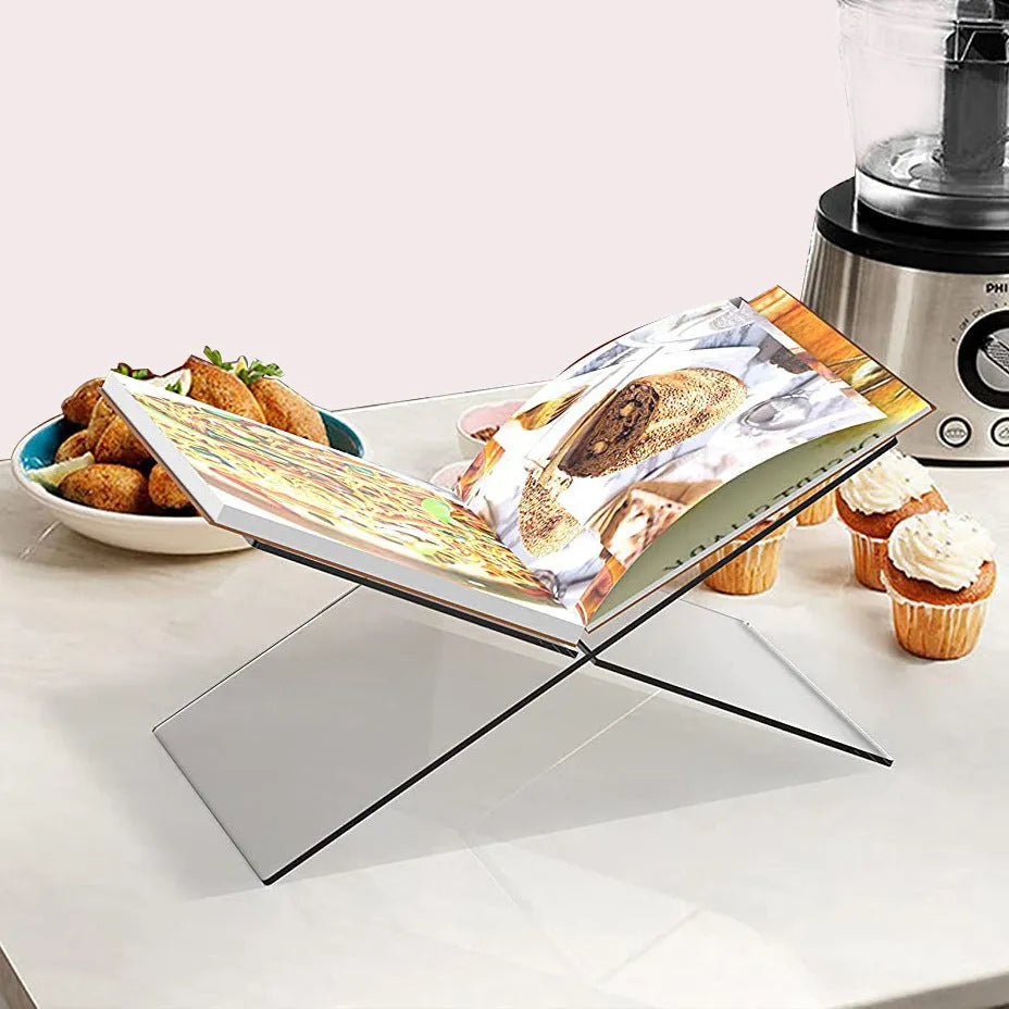 Clear acrylic X-shaped book reading rack holding a book on a desk