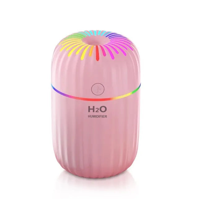 Small white, pink, or green USB-powered mini humidifier with water tank on a desk.