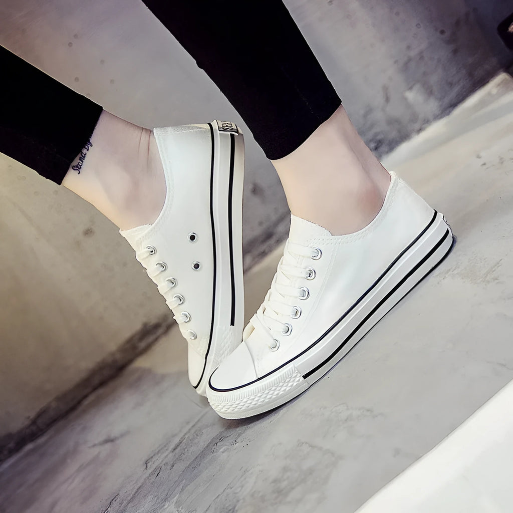 Women's solid-colour canvas shoes in black, shown on a foot from a side angle.