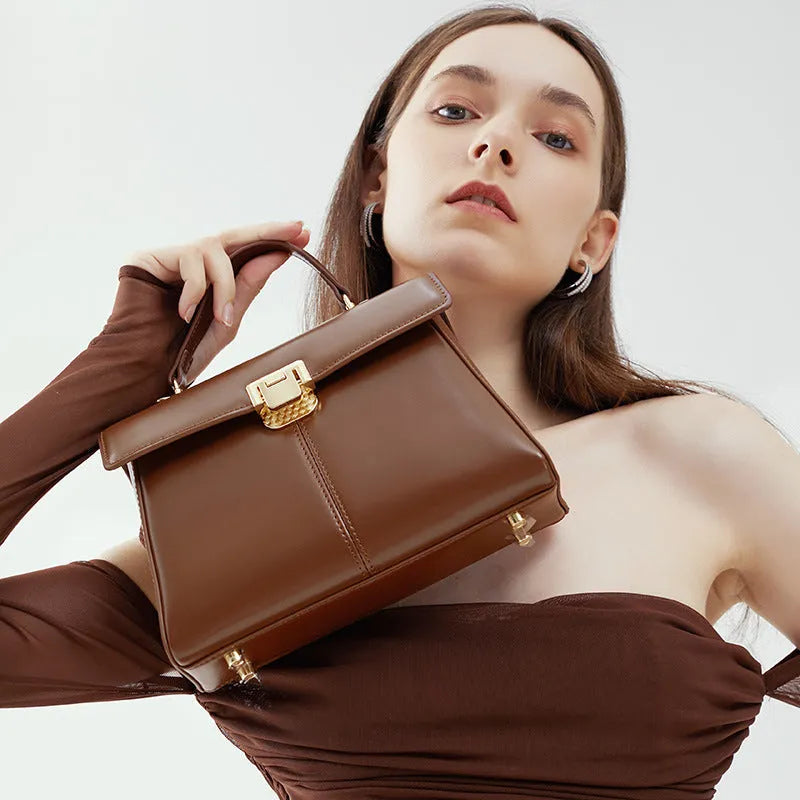 Women's black leather shoulder bag with vachette clasp showing horizontal square shape and shoulder strap