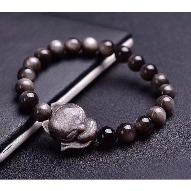 Close-up of a polished black obsidian bracelet bead carved with a detailed fox design.