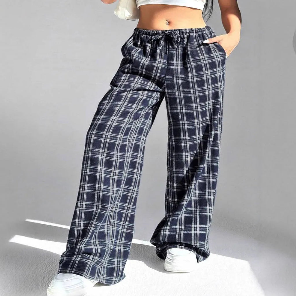 Blue loose fit women's plaid trousers with drawstring waist and pockets on a neutral background.