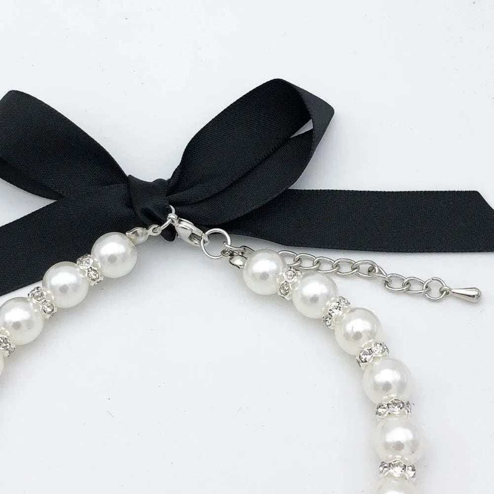 Small dog wearing adjustable pearl and rhinestone necklace with ribbon bow in pink colour