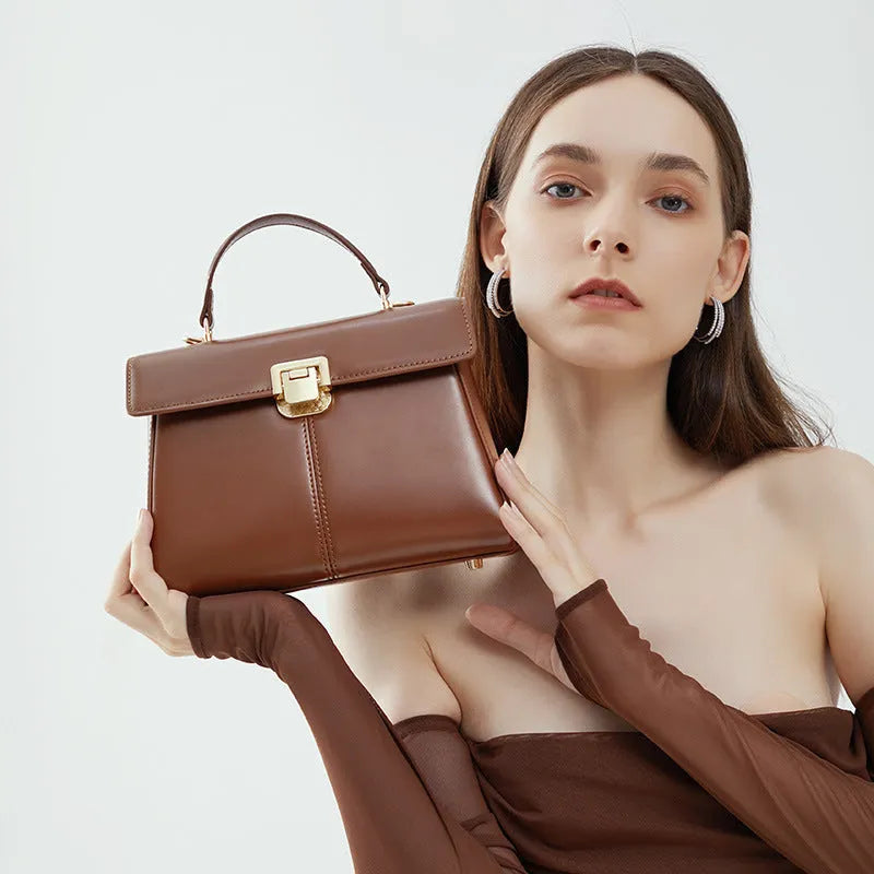 Women's black leather shoulder bag with vachette clasp showing horizontal square shape and shoulder strap