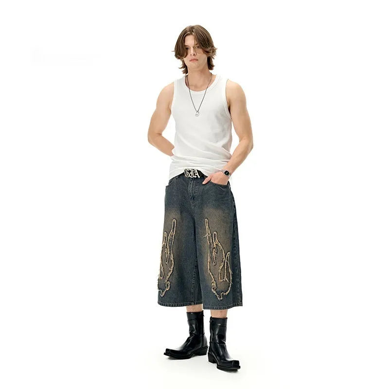 Men's black cropped denim shorts with flame embroidery patch detail on straight leg silhouette