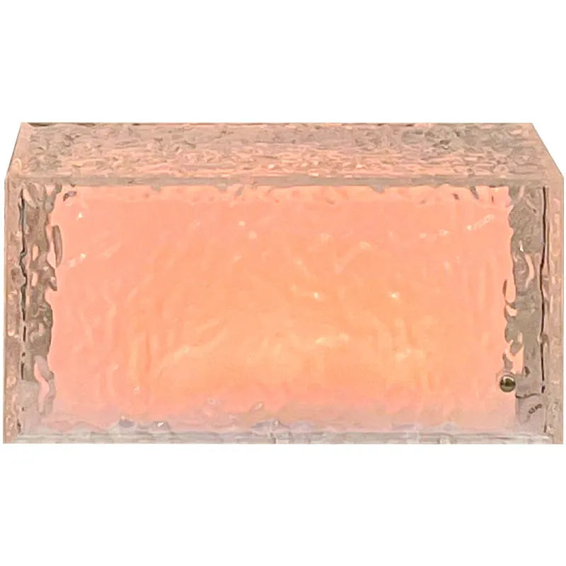 Geometric clear acrylic ice cube shaped night lamp with coloured LED light inside on a wooden table.