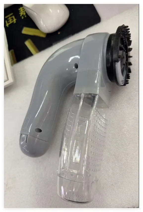 Grey handheld electric pet hair remover and massaging brush with soft rubber head.