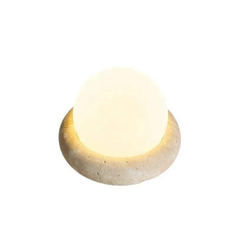 Cream-coloured modern bedside lamp with remote control on a table.