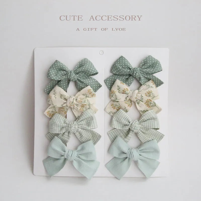 Children's fabric bow hairclip set showing eight different colour patterns including polka dots and floral designs