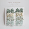 Children's fabric bow hairclip set showing eight different colour patterns including polka dots and floral designs