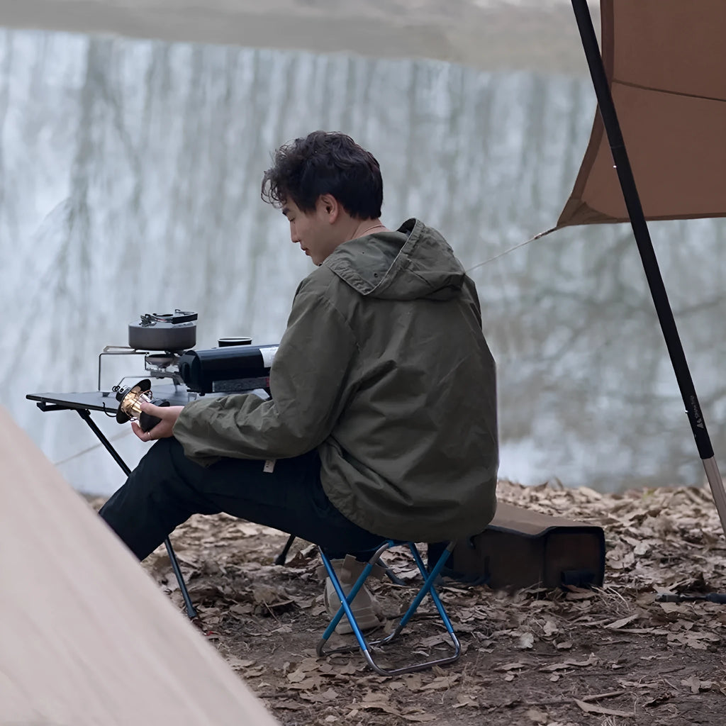 Black aluminium alloy folding stool shown in a folded position for portable storage.