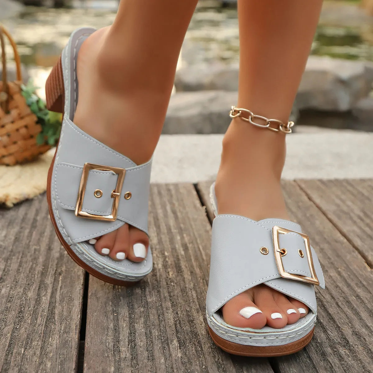 Women's black slippers with a chunky heel, metal buckle strap, and round toe on a rubber sole.