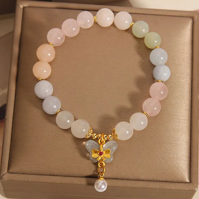Close-up of a women's crystal bracelet with a colourful natural morganite and jade butterfly pendant.