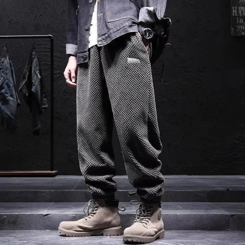 Man wearing grey straight-leg casual sweatpants with an ankle-tied design detail.