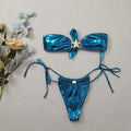 Glossy blue women's tube top bikini with gold starfish print on a beach.