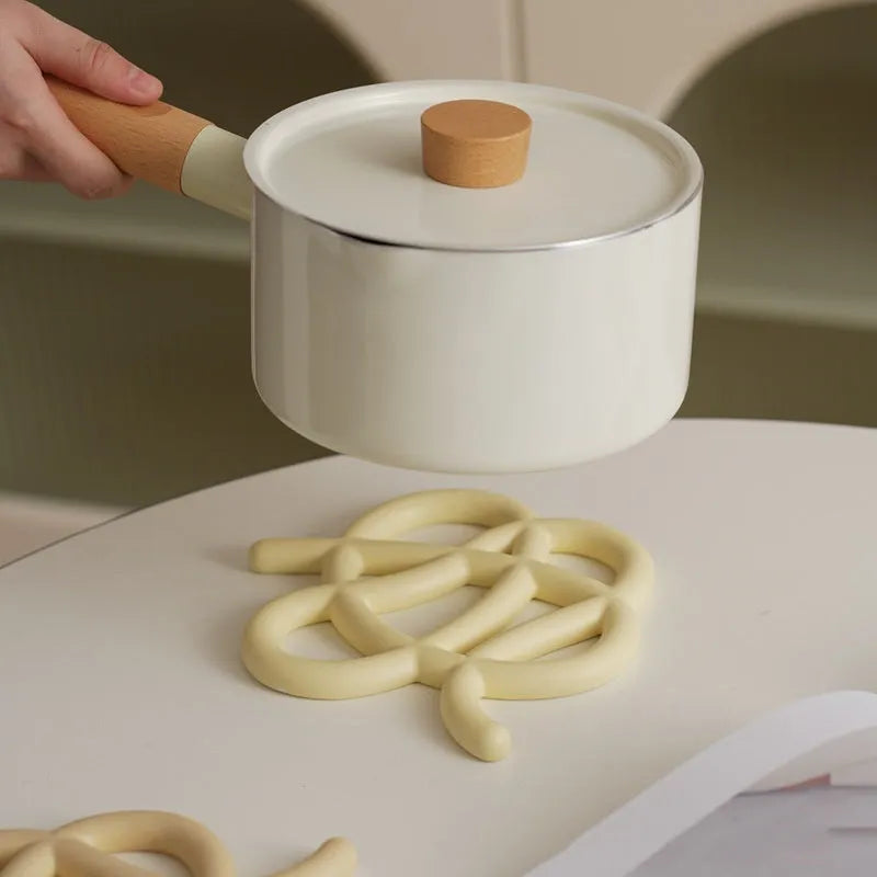 Ceramic heat proof mat in an irregular shape on a wooden table.