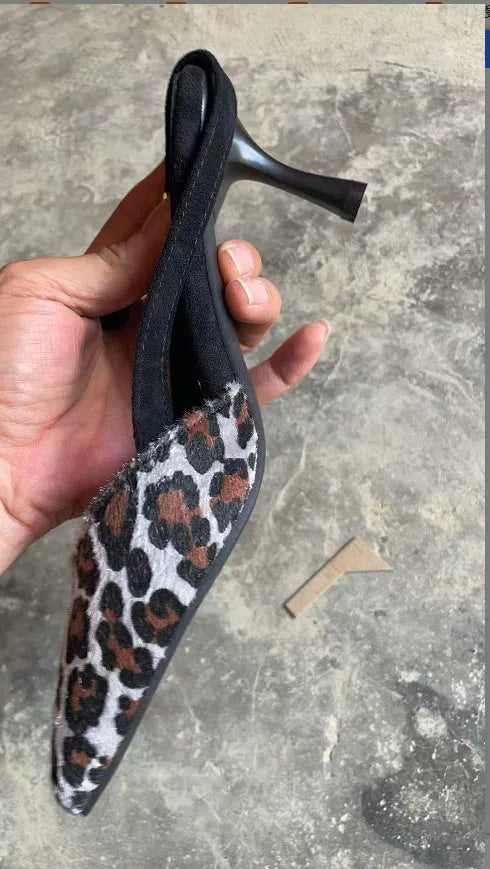 Leopard print women's suede sandals with a scattered pointed toe and high heel on a neutral background.
