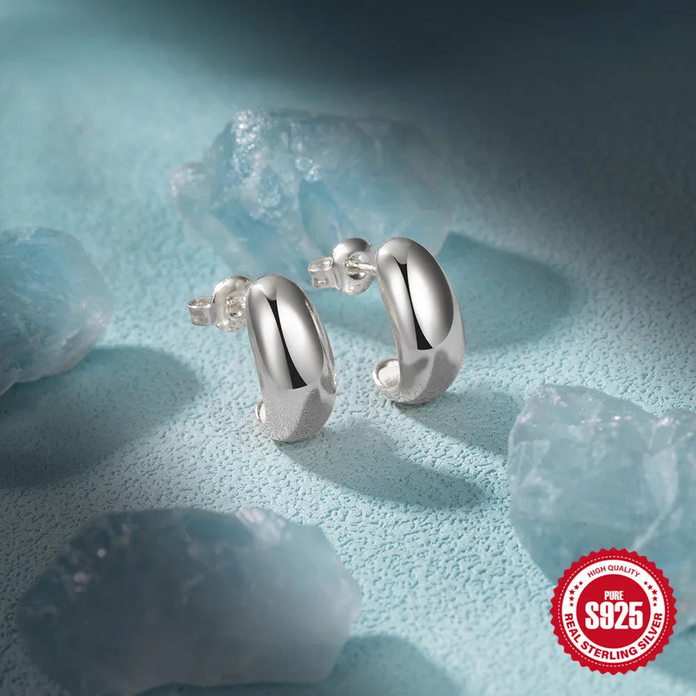 A single C-shaped sterling silver stud earring with a glossy gold or silver electroplated finish.