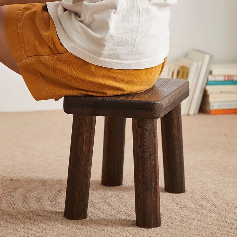 Distressed solid wood changing stool with bracket structure in a rustic finish.