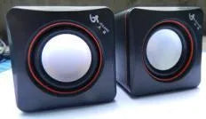 Small square black USB-powered 2.0 computer speaker on a desktop.