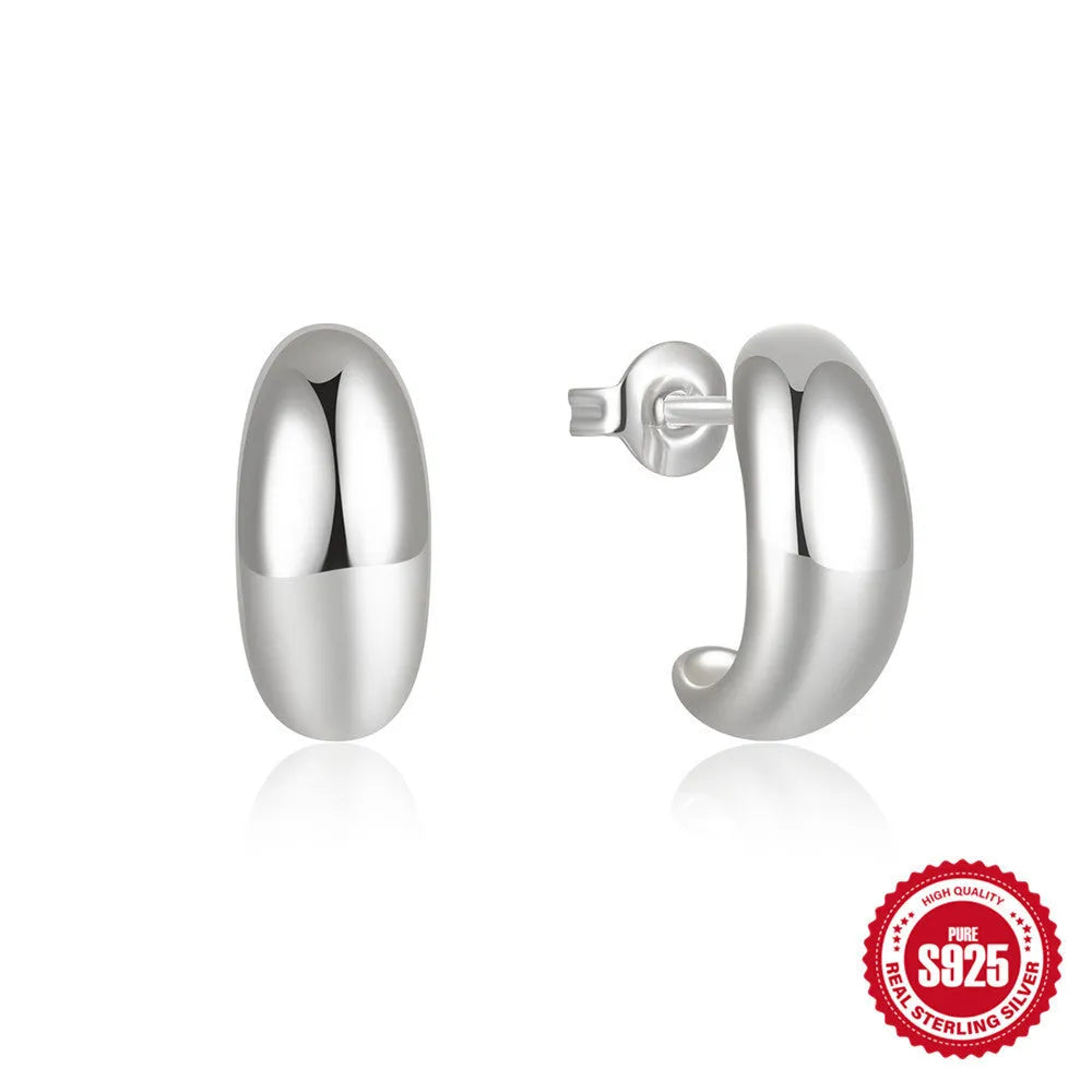 A single C-shaped sterling silver stud earring with a glossy gold or silver electroplated finish.