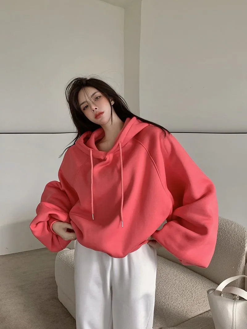 Watermelon red women's loose hooded sweater made from mulberry silk fabric on a hanger.